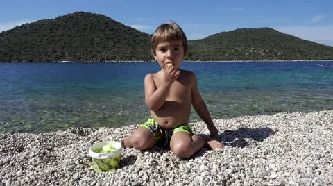 Child eats pieces of mellon on the beach. Stock Footage 66185938