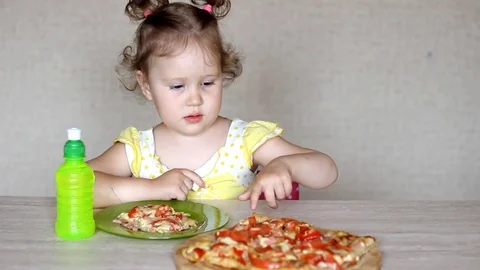 The child eats pizza and drinks lemonade. Cafe and fast food. Little funny girl Video stock 79886908