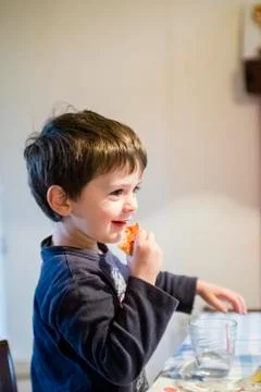 Child eats pizza sitting at the kitchen table Stock Photos