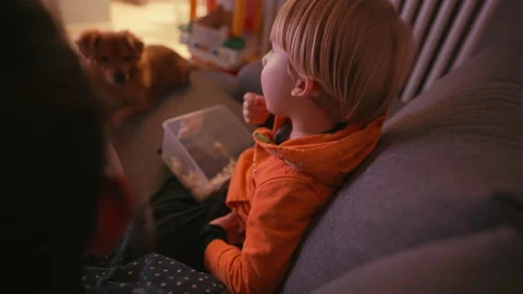 A child eats popcorn while watching tv Stock Footage 146309656
