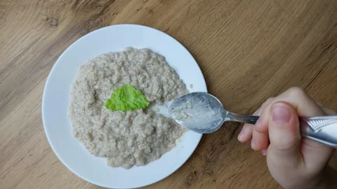 A child eats porridge with a lettuce leaf with a spoon. Fiber, grains, healthy Stock Footage 263190500