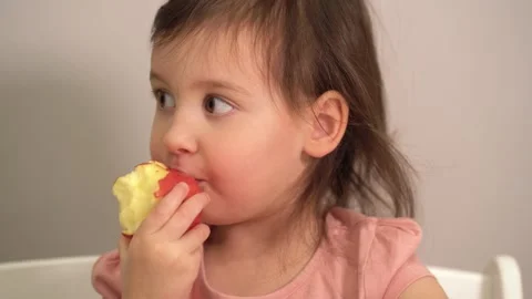 A child eats a red apple. Close-up of the face of a child who eats. A girl in a Video stock 167250294