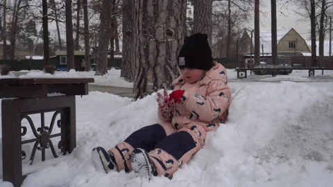 A child eats snow and chupachups while sitting on a pile of snow Stock Footage 262673496