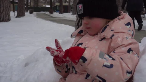 A child eats snow and chupachups while sitting on a pile of snow Stock Footage 262674181