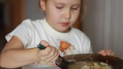 Child eats soup. Close up portrait of a Baby girl sitting at the table of home Stock Footage 120111473