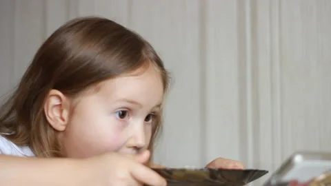Child eats soup with a spoon and and looks video on a smartphone. Closeup baby Stock Footage 122432039