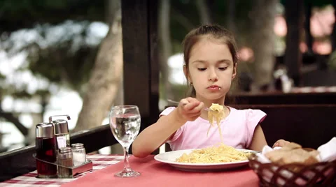 Child eats spaghetti pasta in the restaurant which is located on the shore Stock Footage 39829504