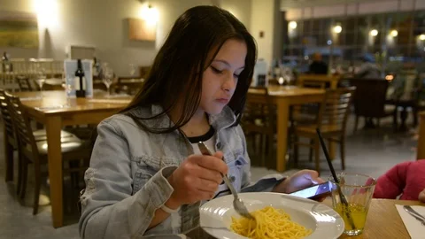 Child eats spaghetti pasta in the restaurant. Low light selective focus. 動画素材 101664964