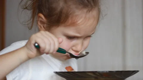 Child eats with spoon soup. Lunch Close up portrait of a Baby girl sitting at Stock Footage 122431283