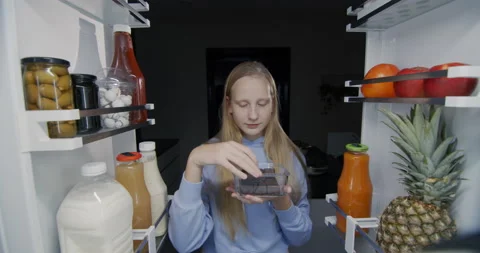 The child eats sweets at the refrigerator. Nighttime snacking and junk food Stock Footage 225455705