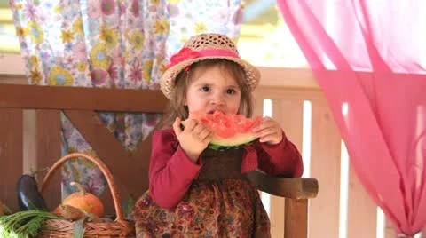 Child eats a tasty water-melon, sitting on a summer veranda Stock Footage