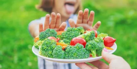 Child eats vegetables broccoli and carrots. Selective focus. Stock Photos