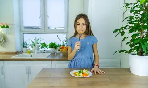 The child eats vegetables on a chair. Selective focus. Stock Photos