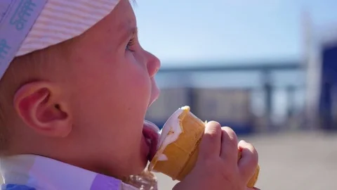 The child eats a waffle cup ice cream in park at closeup Vídeo Stock 76323100