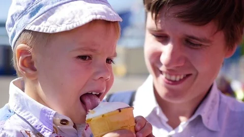 The child eats a waffle cup ice cream in park at closeup. Family holiday in the Vidéo 76488388
