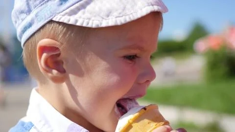 The child eats a waffle cup ice cream in park at closeup Stock Photos