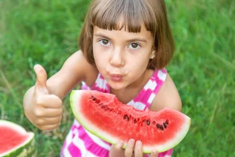 Child eats a watermelon in the garden. Selective focus. Stock Photos
