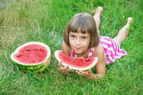 Child eats a watermelon in the garden. Selective focus. Stock Photos