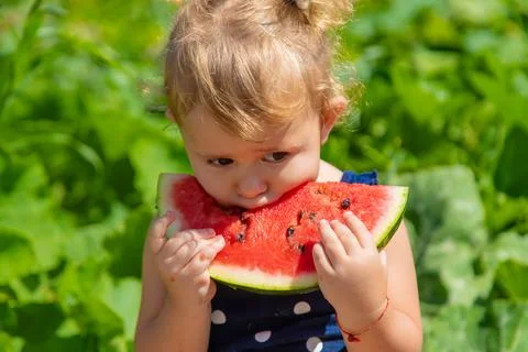 A child eats watermelon in the park. Selective focus. Stock Photos
