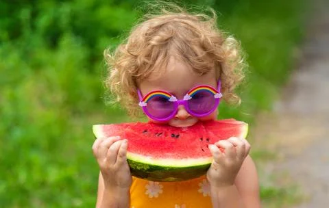 A child eats watermelon in the park. Selective focus. Stock Photos