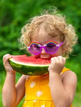 A child eats watermelon in the park. Selective focus. Stock Photos