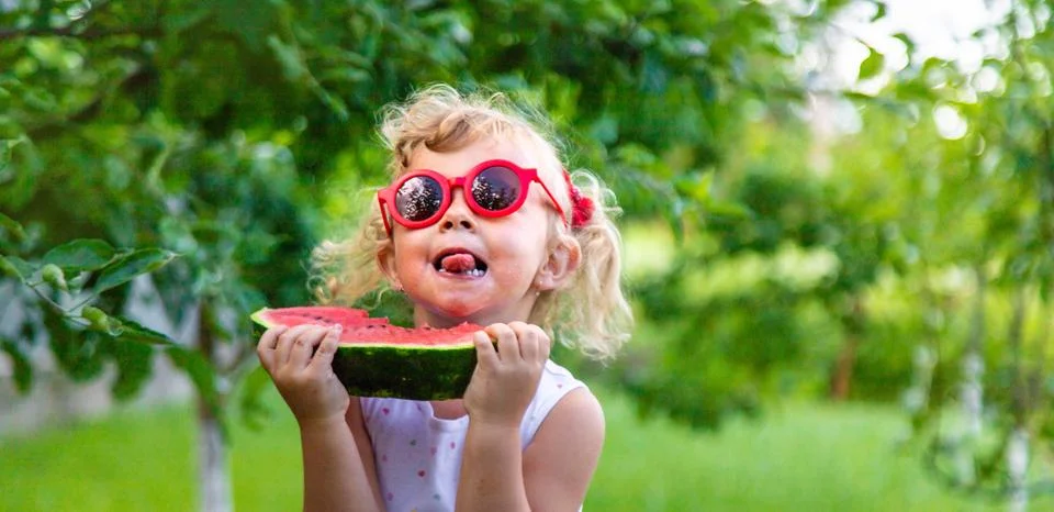 A child eats a watermelon in the park. Selective focus. Stock Photos
