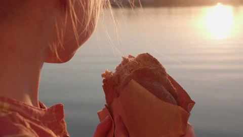 A child eats a whole grain bun by the river. Stock Footage 135743118