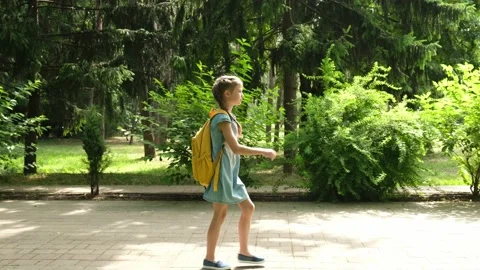 Child elementary school student walks through the park to school in the morning Stock Footage 199540772