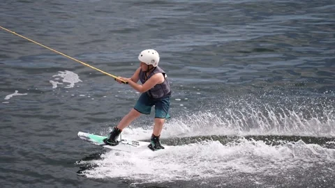 The child is engaged in cable wakeboarding on the pond in the wake park. Stock Footage 247643664