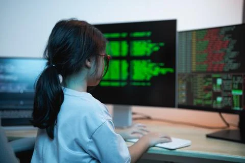 Child Engaged in Computer Programming with Multiple Monitors Displaying Cod.. 写真素材