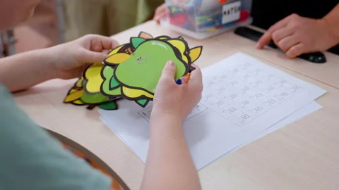 Child engaged in creative activity, coloring vibrant paper cutouts while Stock Footage 319533097