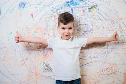 The child is engaged in creative work at home. A boy stands by the wall paint Stock Photos