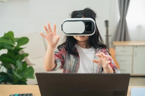 Child Engaged in Virtual Reality Experience with Headset and Laptop in Brig.. Stock Photos