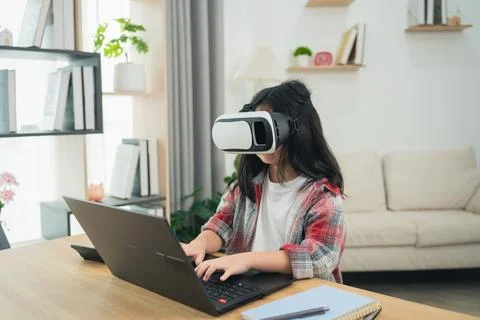 Child Engaged in Virtual Reality While Using Laptop in Modern Home Workspac.. Stock Photos