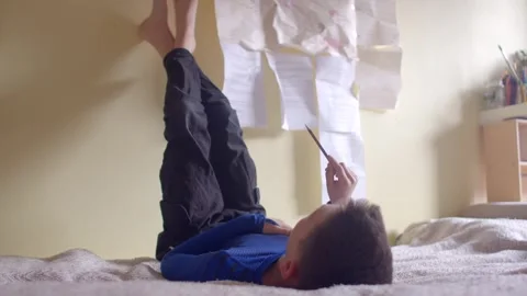 Child Engaged in Writing on Their Bed Surrounded by Papers on the Wall Stock Footage 311206249