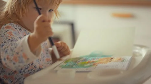 Child engages in creative painting activity while sitting on a chair indoors Stock Footage 331300029