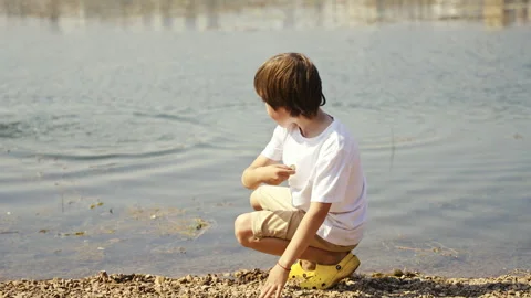 A Child Engaging in Fun Exploration of Nature by the Waters Edge During Summer Stock Footage 313327951