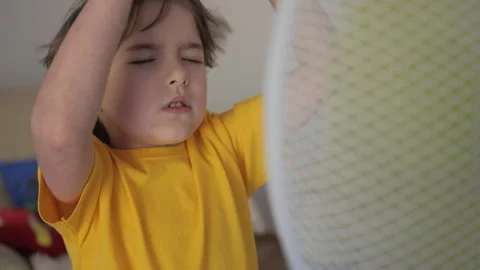 Child Enjoying Cool Wind From Electric Fan at Home at Summer Heat Weather. .. Stock Footage 343653238