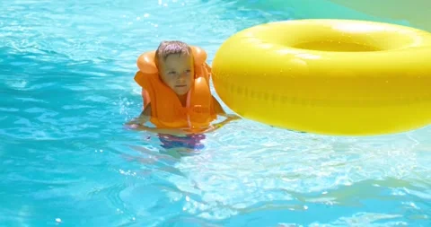 Child Enjoying Pool Time with Yellow Inflatable Ring Stock Footage 324939476