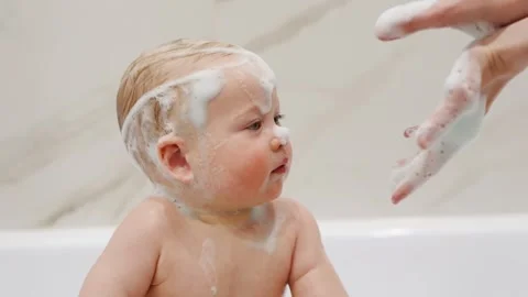 Child enjoys bath time with bubbles in a bathroom setting Stock Footage 335941731