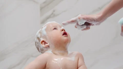 Child enjoys bath time with soap and water in home bathroom Stock Footage 335941665