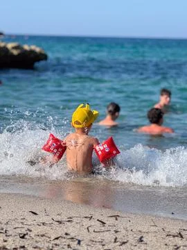 Child Enjoys Beach Waves with Floaties Foto stock