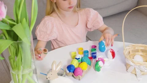 A child enjoys coloring Easter eggs at a bright table Stock Footage 302043549