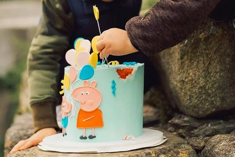 Child enjoys decorating a cake by adding colorful items outdoors in a garden  Stock-Fotos