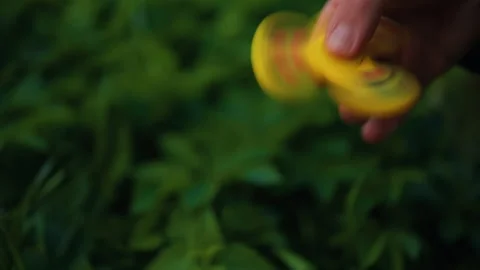 A Child Enjoys Playing with a Bright Yellow Fidget Spinner While Sitting in a Stock Footage 308335220