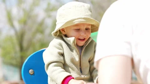 Child enjoys playtime on a swing set at the park in spring Stock Footage 335218184