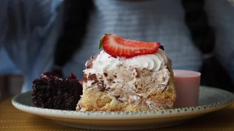 Child enjoys a slice of cake topped with chocolate and strawberry Stock Footage 336770520
