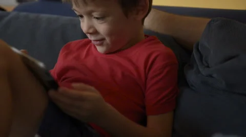 Child enter in focus and play with tablet on sofa at home with his dad 動画素材 64542884
