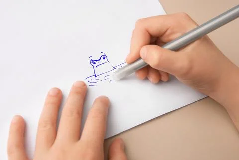 Child erasing drawing with erasable pen on paper sheet against beige backgr.. Stock Photos