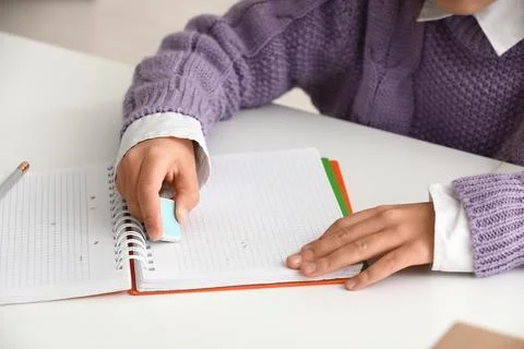 Child erasing mistake in notebook at table, closeup Foto stock